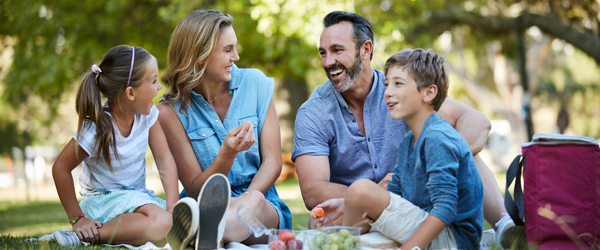 Family sitting outside and eating a picnic.